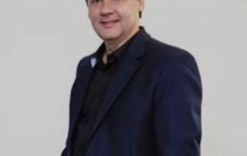 Homem branco de terno azul sobre fundo branco.