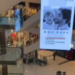 Cenário de shopping com escadas se cruzando. Em primeiro plano, banner com foto de bebê e adulto sorrindo, texto "Dia dos Pais. Para cada tipo de pai existe um Shopping Villa Lobos diferente."