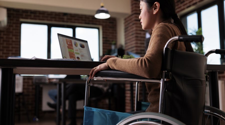 Mulher com em cadeira de rodas olhando um computador.